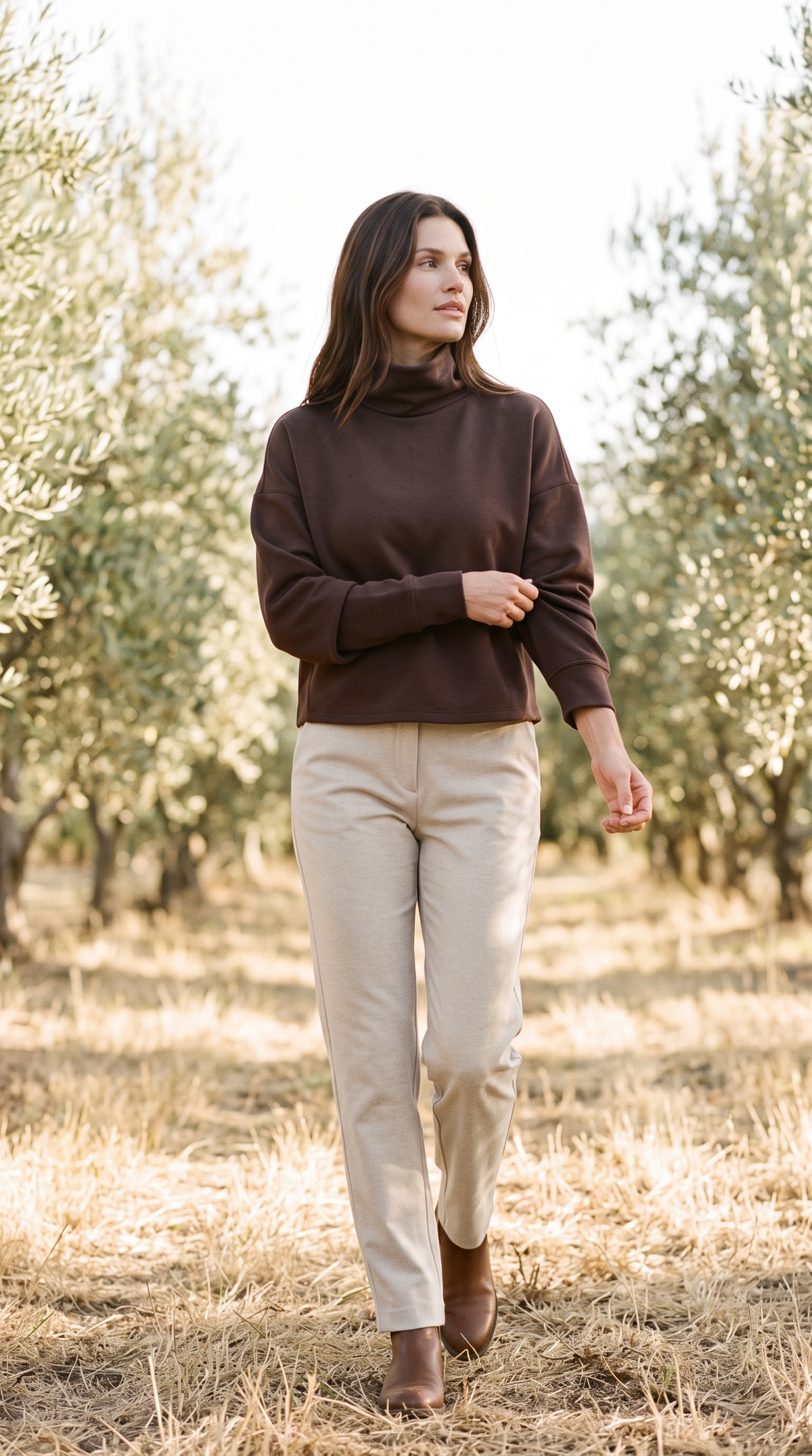 Rhone DreamGlow Mock Neck in Dark Espresso with pale oat trousers, in a sunlit olive grove in Napa Valley after the October harvest.