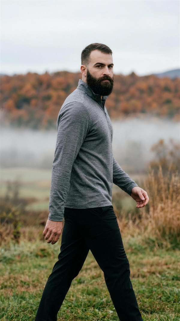 Heater Pro 1/4 Zip - Heather Grey — Stowe: the heather grey quarter-zip with its tall stand collar and open placket, worn with a black technical trouser, walking a misty Vermont valley rise under a rust maple ridge