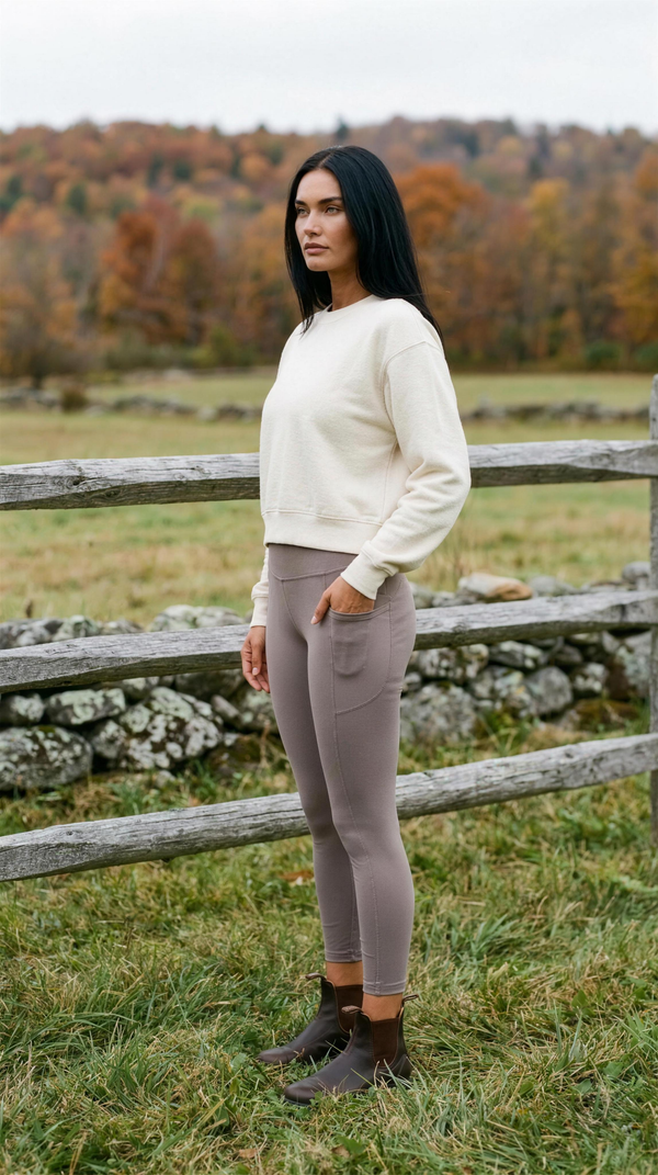 Rhone Revive 7/8 Pocket Legging in Smokey Taupe with a cream sweatshirt, at a split-rail pasture fence outside Stowe, Vermont in mid-October.